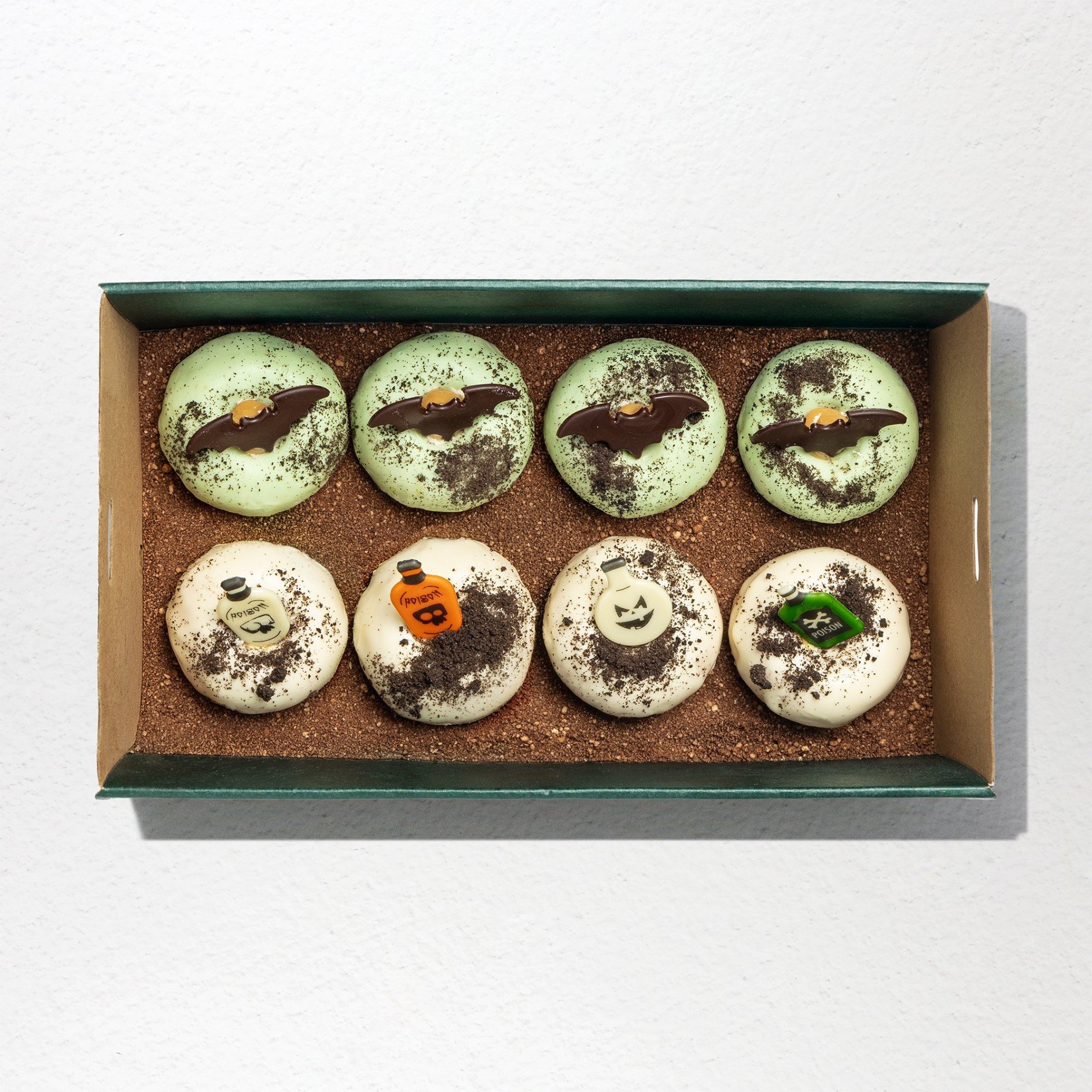 Bite sized donuts topped with Oreo crumbs, 6 donuts glazed with light green icing with bats, 6 donuts with white glazing topped with chocolate jar ornaments