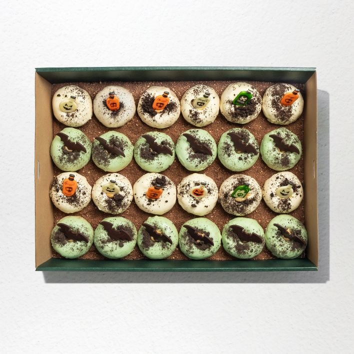 Bite sized donuts topped with Oreo crumbs, 12 donuts glazed with light green icing with bats, 12 donuts with white glazing topped with chocolate jar ornaments