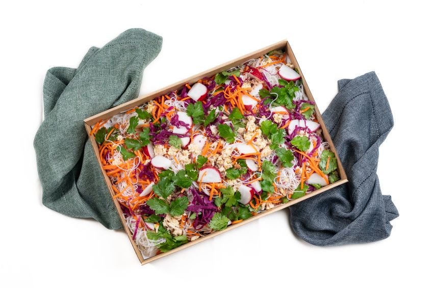 Lemongrass chicken vermicelli salad with cabbage, carrot, radish, herbs and crispy shallots in a catering box.