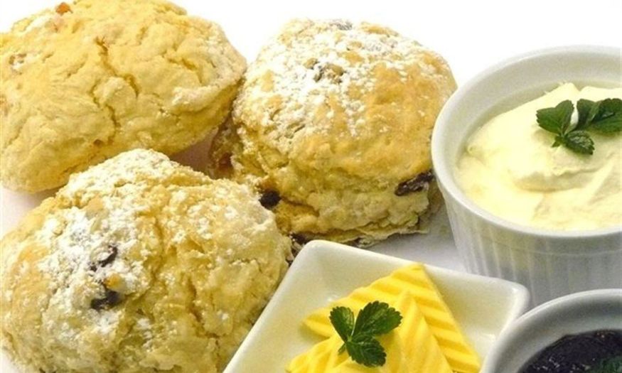Scones with freshly whipped cream, butter, jam and utensils.
