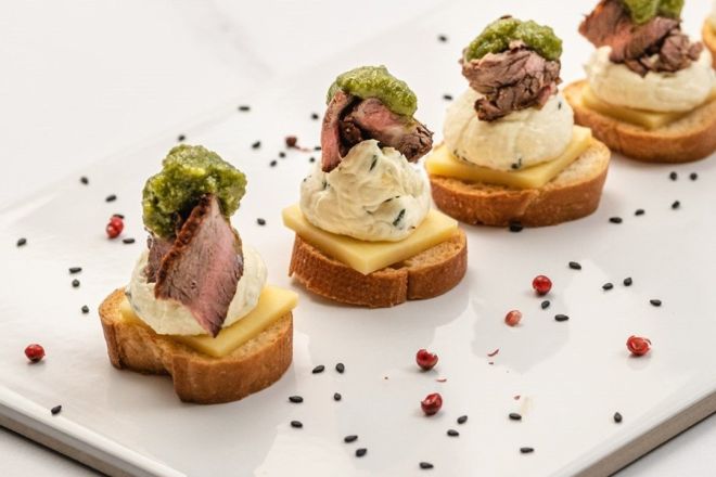 SEARED BEEF & CREAMY HORESRADISH CROSTINI with cheddar cheese square & topped with basil pesto 