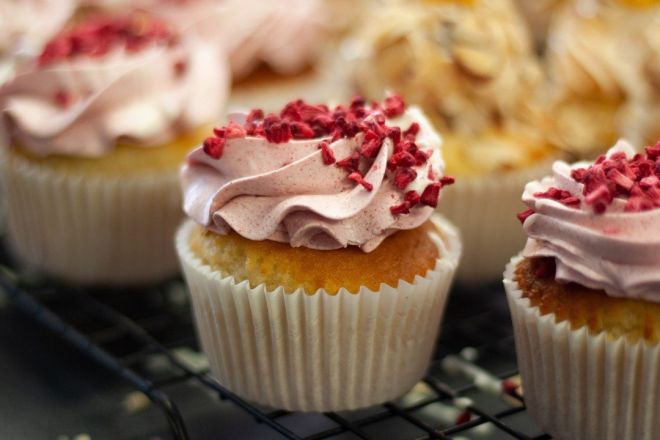 VANILLA BEAN & RASPBERRY CUPCAKES topped with raspberry buttercream & sprinkled with freeze dried raspberries - presented on a black biodegradable platter 