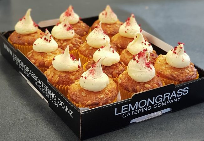 LEMON COCONUT CUPCAKES - topped with pinenuts, lemon mascarpone cream frosting, toasted coconut & freeze dried raspberries - presented on a black biodegradable platter 