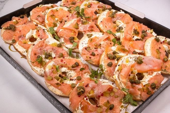 SMOKED SALMON OPEN BAGEL HALVES with cream cheese, smoked salmon slices, fresh herbs, capers & thin sliced pickled red onion 