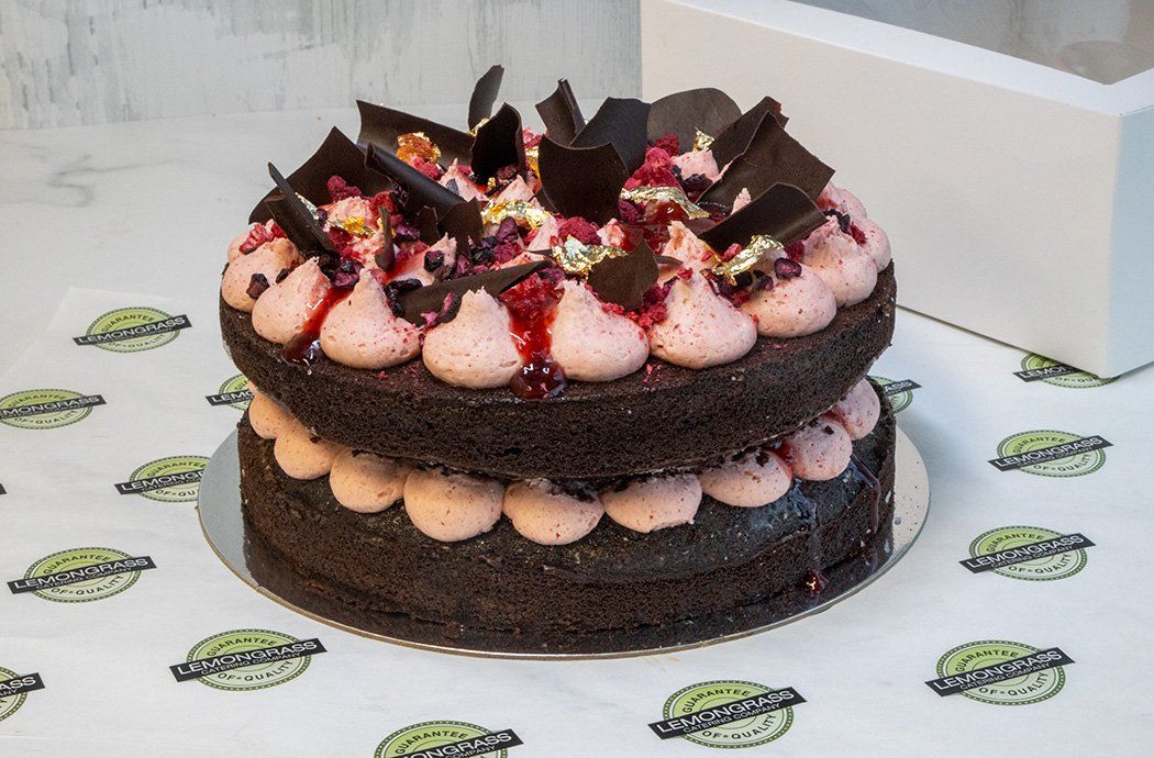 CHOCOLATE AND RASPBERRY CAKE - 23cm round - double cake layer filled & topped with raspberry buttercream, drizzled with berry couli and decorated with freeze dried raspberries & Whitakers chocolate shards. Presented in a cake box