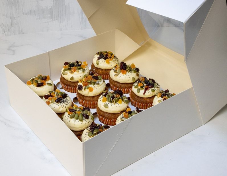 CARROT CAKE CUPCAKE BOX (12) - with chopped walnuts, decorated with zesty cream cheese icing topped with dried apricots, pumpkin seeds & dried cranberries  - in cupcake box with lid 