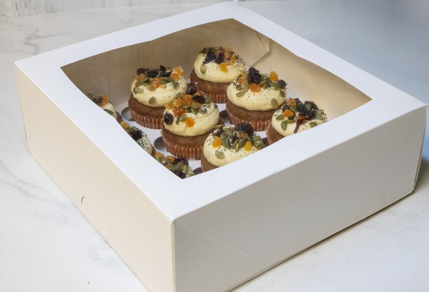 CARROT CAKE CUPCAKE BOX (12) - with chopped walnuts, decorated with zesty cream cheese icing topped with dried apricots, pumpkin seeds & dried cranberries  - in cupcake box with lid 