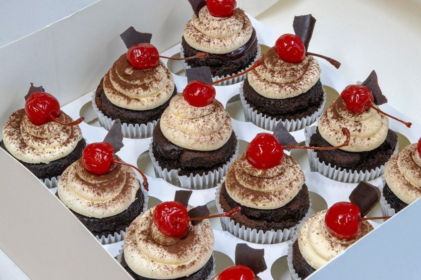BLACK FOREST CUPCAKES - Chocolate cupcakes filled with black cherry compote, topped with mascarpone frosting, maraschino cherry & dark chocolate shards - presented on black biodegradable platter 