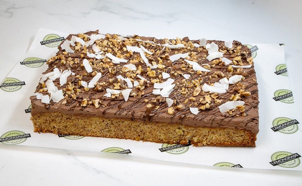 BANANA CAKE SLAB - 25 x 30 cm - Classic banana cake topped with a rich chocolate icing, chopped nuts & coconut shards. Served whole