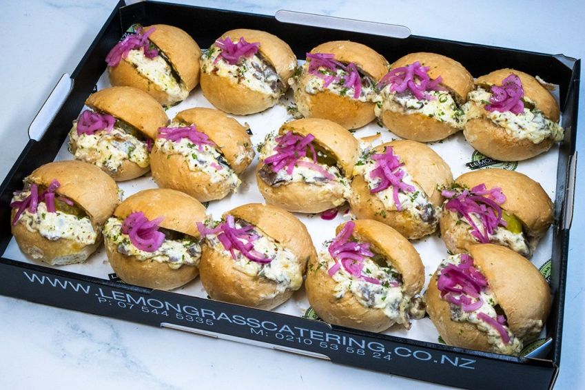 PHILLY-STYLE SHREDDED BEEF MELT with rich cream cheese, cheddar, caramelized onions in soft round midi roll topped with pickled red onions & heated in oven - served hot