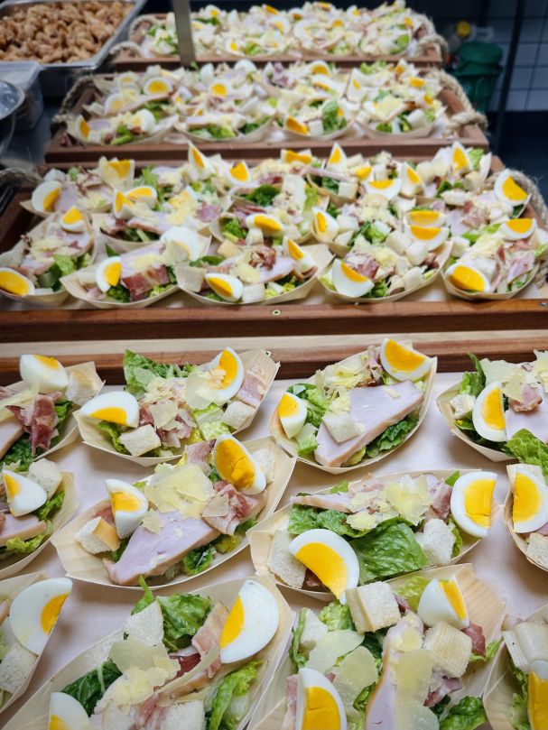 Chicken Caesar Salad with Honey-Cured Streaky Bacon, Anchovies, Garlic Croutons, Egg, and Parmesan Cheese Served in a Bamboo Boat
